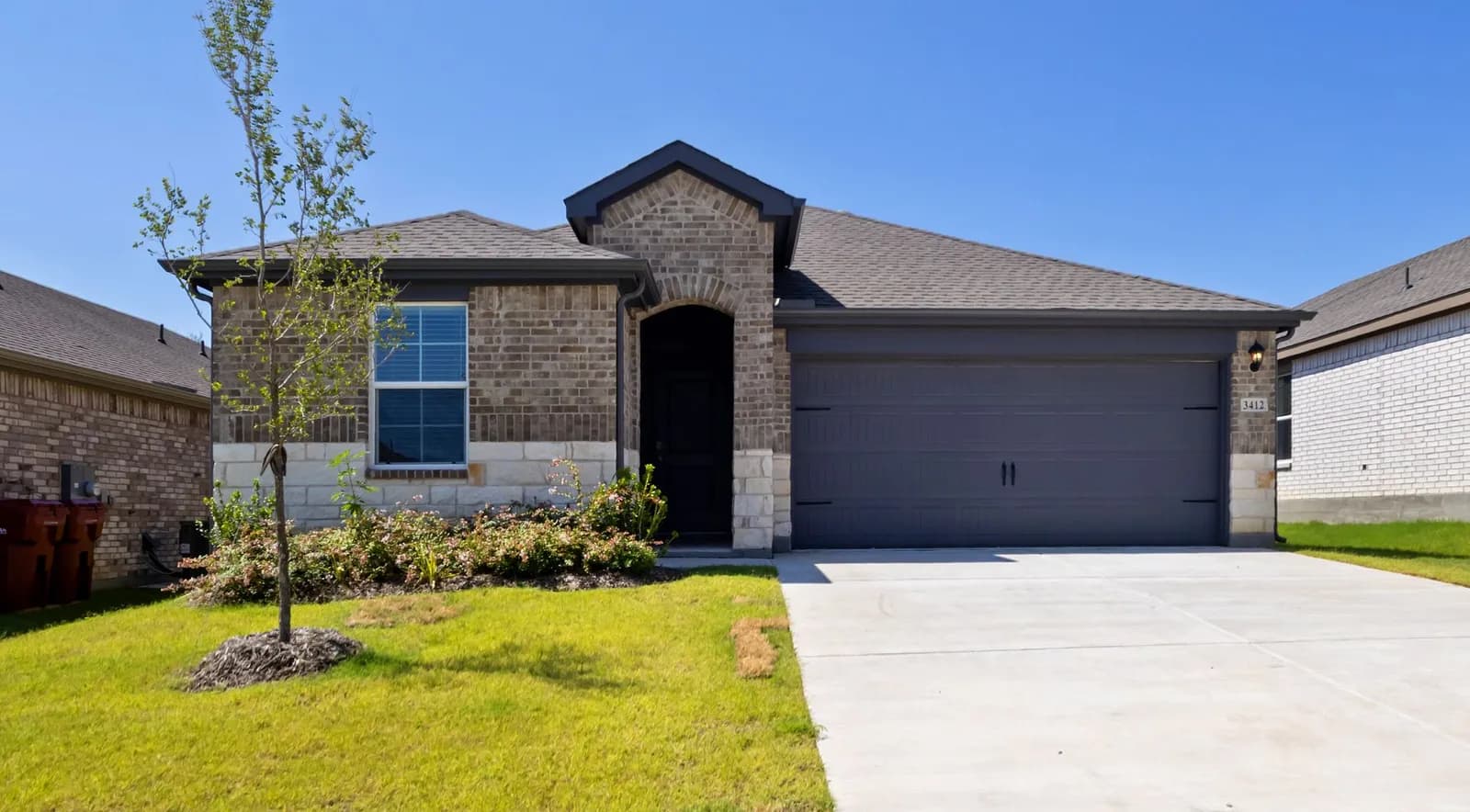 A new-construction brick rental home in the Dallas area with a two-car garage and fresh sod