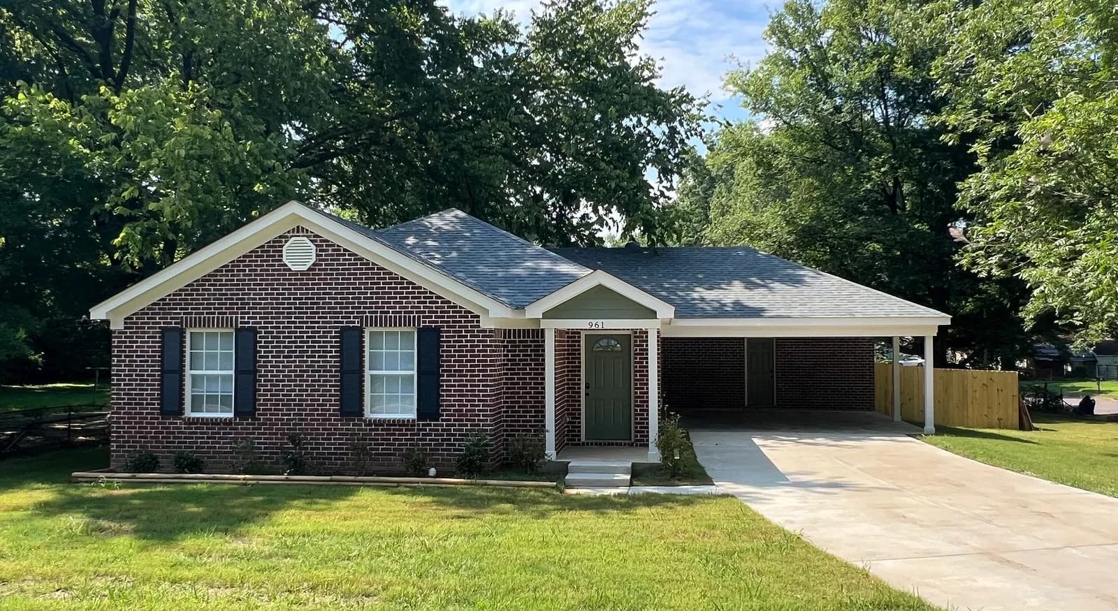A brick Mid South Home Buyers rental home in Memphis with a carport and fresh lawn